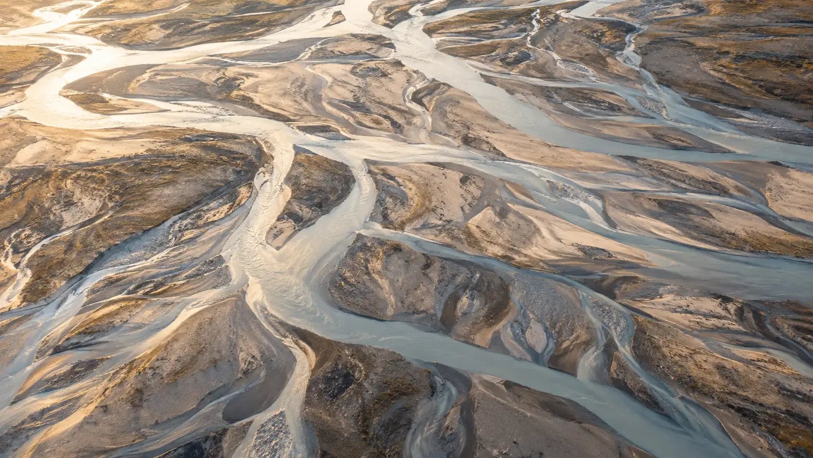 Aerial view of a river carving new channels across sand, illustrating how attachment styles change over time.