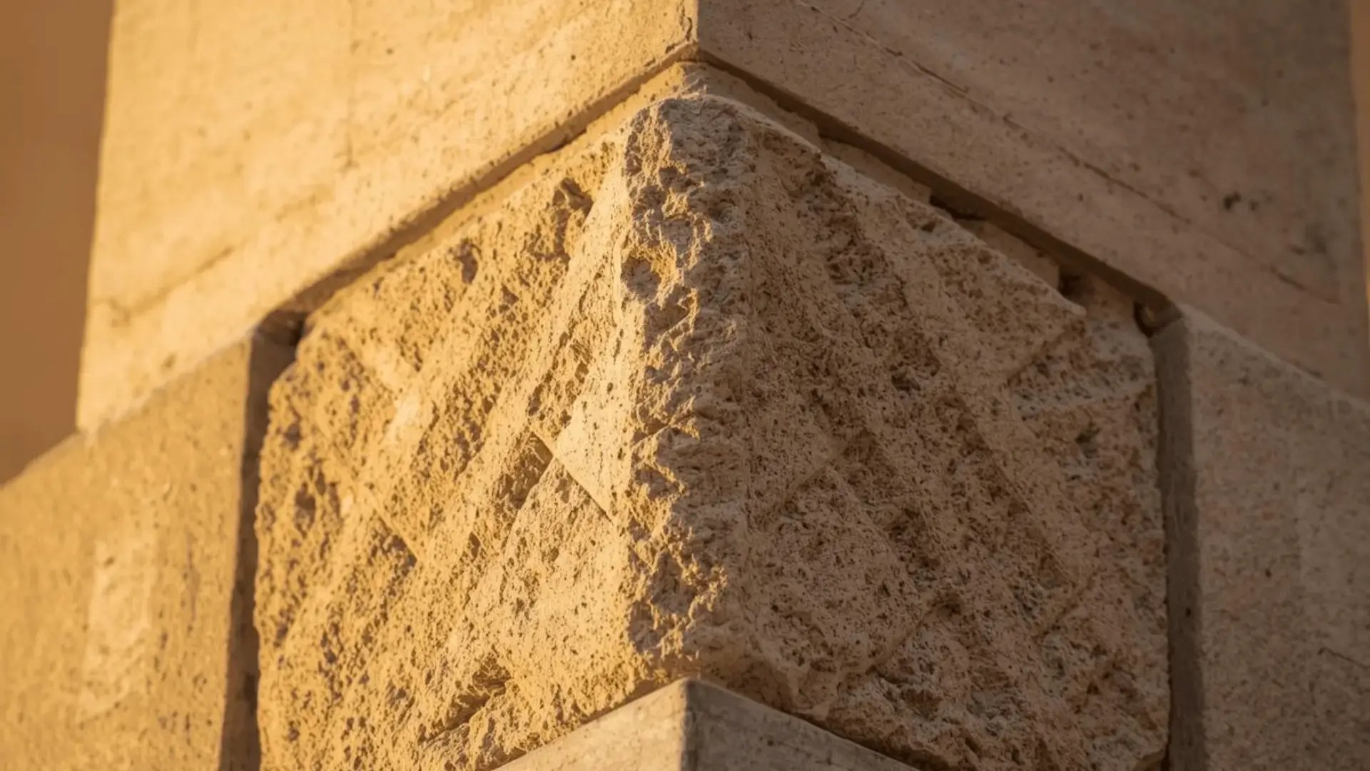 Close-up of a textured cornerstone where two stone walls meet, bathed in warm golden light Trauma Therapist Institute