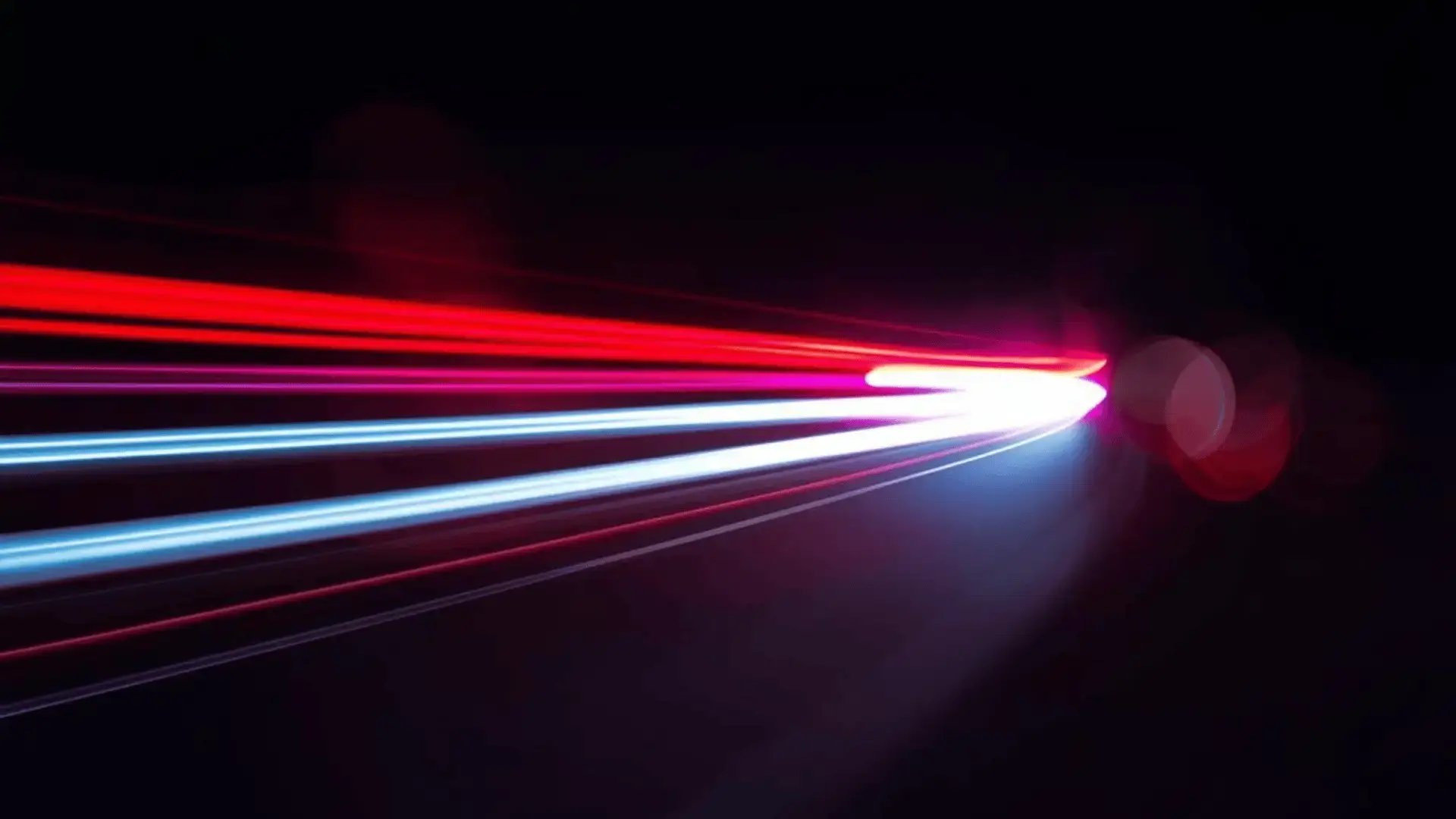 Long-exposure light trails in red and blue sweeping across a dark background, evoking bilateral movement Trauma Therapist Institute