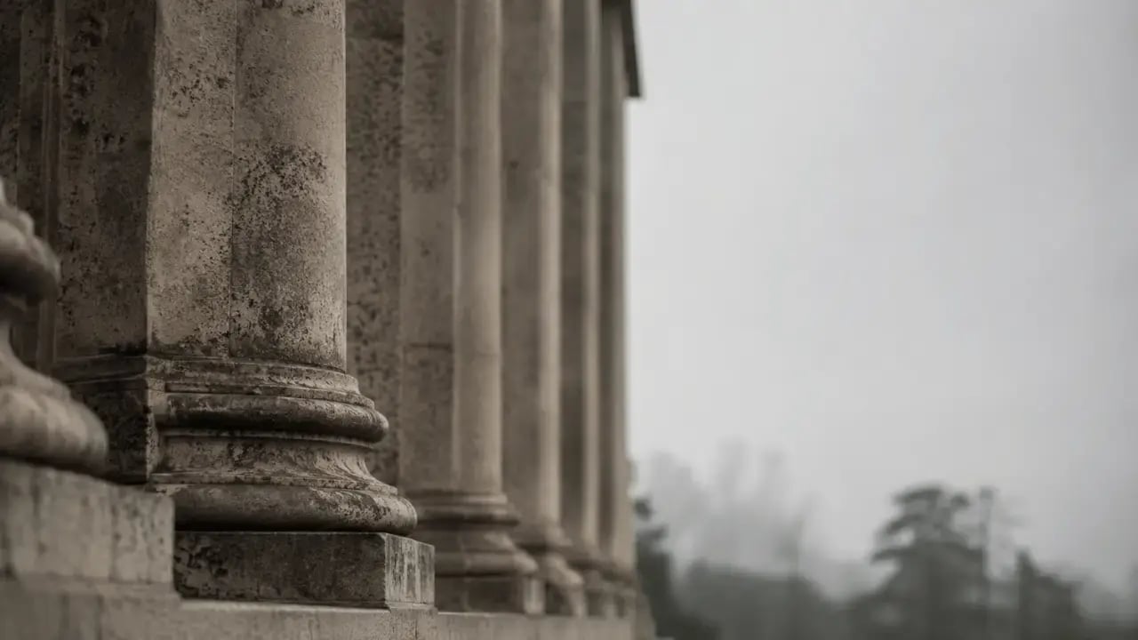 Stone columns of a federal research institution in muted morning light, representing the public infrastructure that supports trauma science.